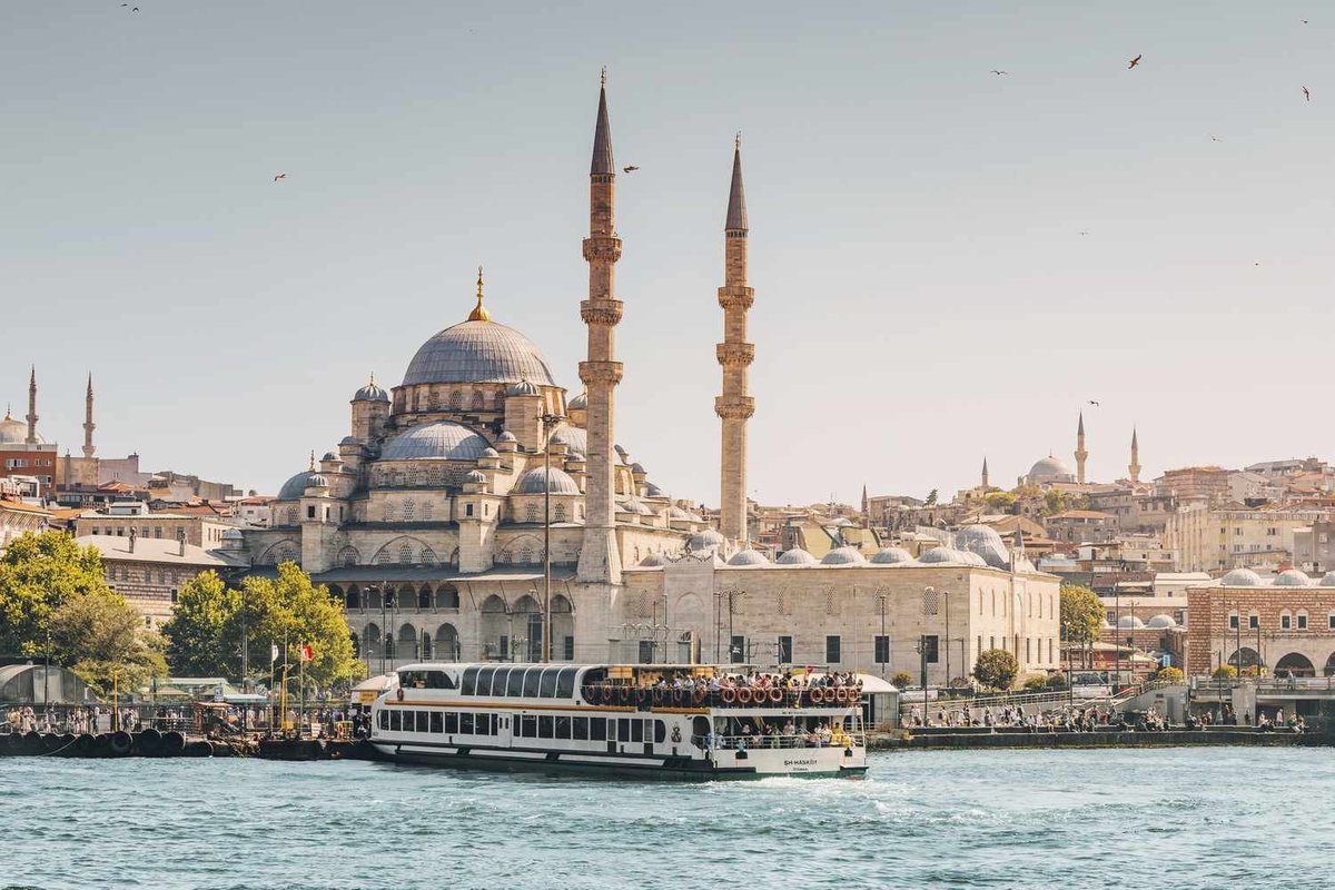 Istanbul seen from the water: a mosque with tall minarets and a ferry crossing in front of it